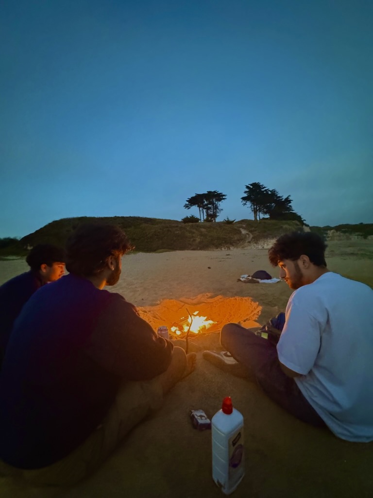 Friends sitting around a small bonfire on 4 Mile Beach near Santa Cruz at dusk